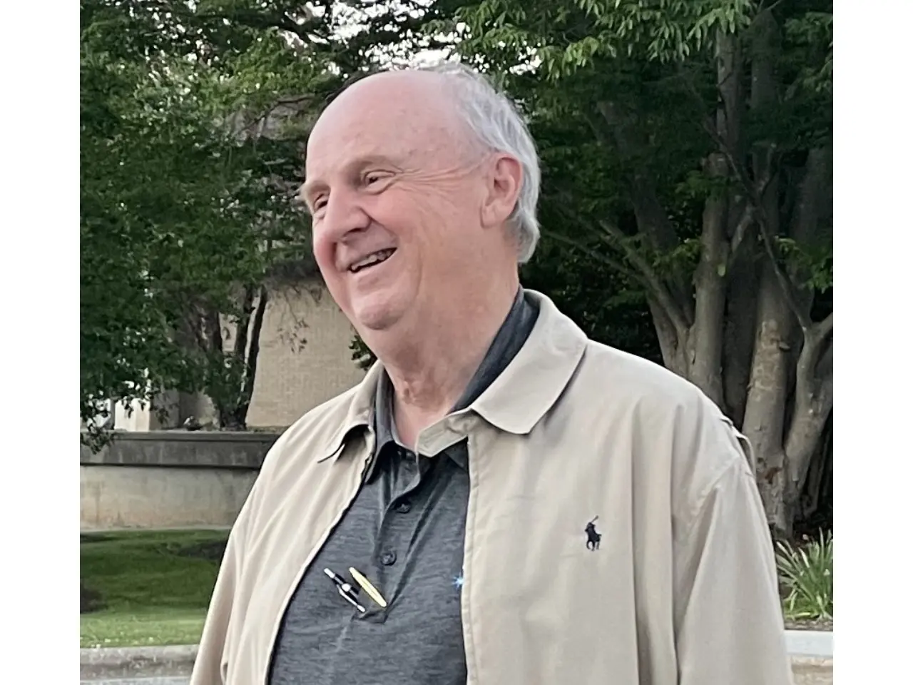 Smiling man wearing a beige jacket.