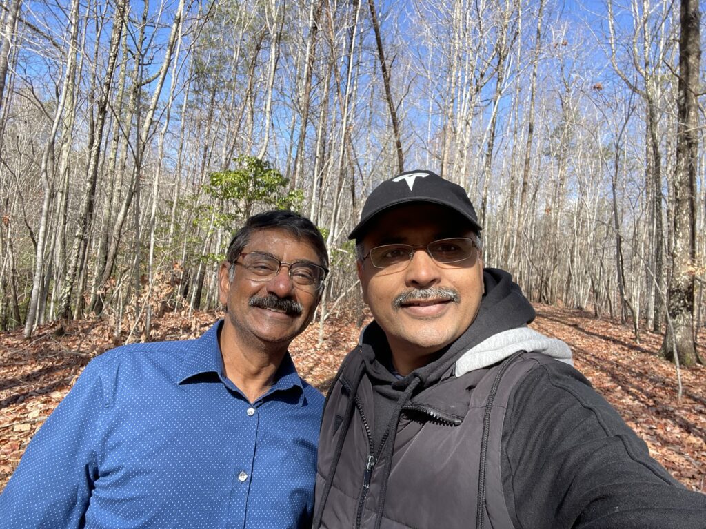 Two men standing in front of a forest.