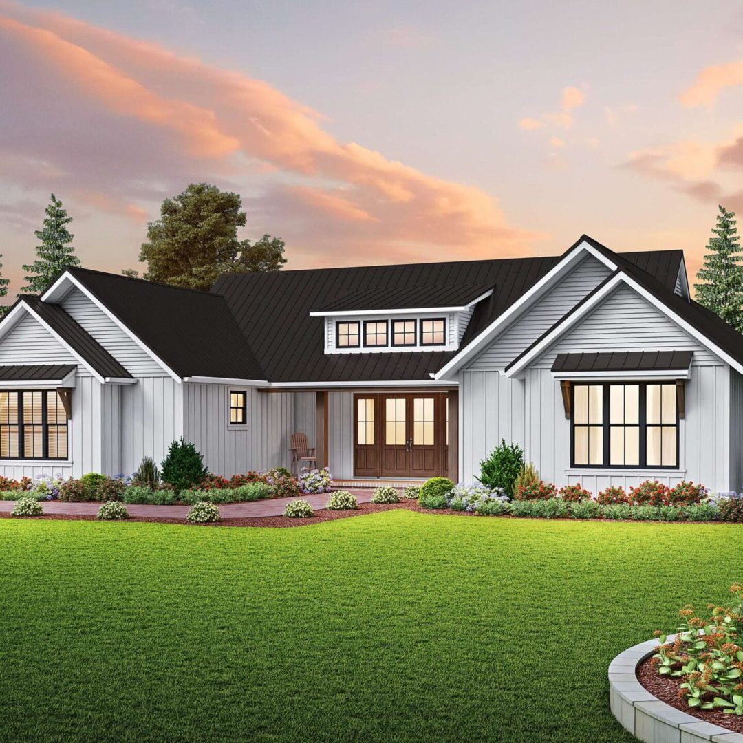 White farmhouse with black roof and lawn.